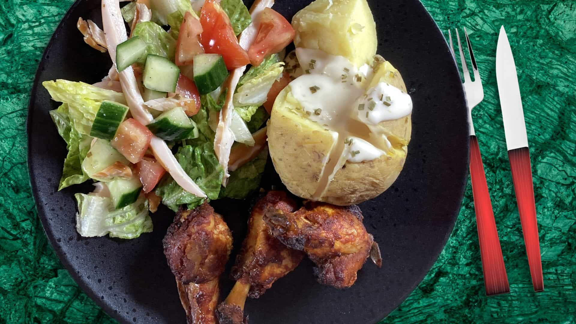 Gepofte aardappel met caesarsalade en kipdrumsticks